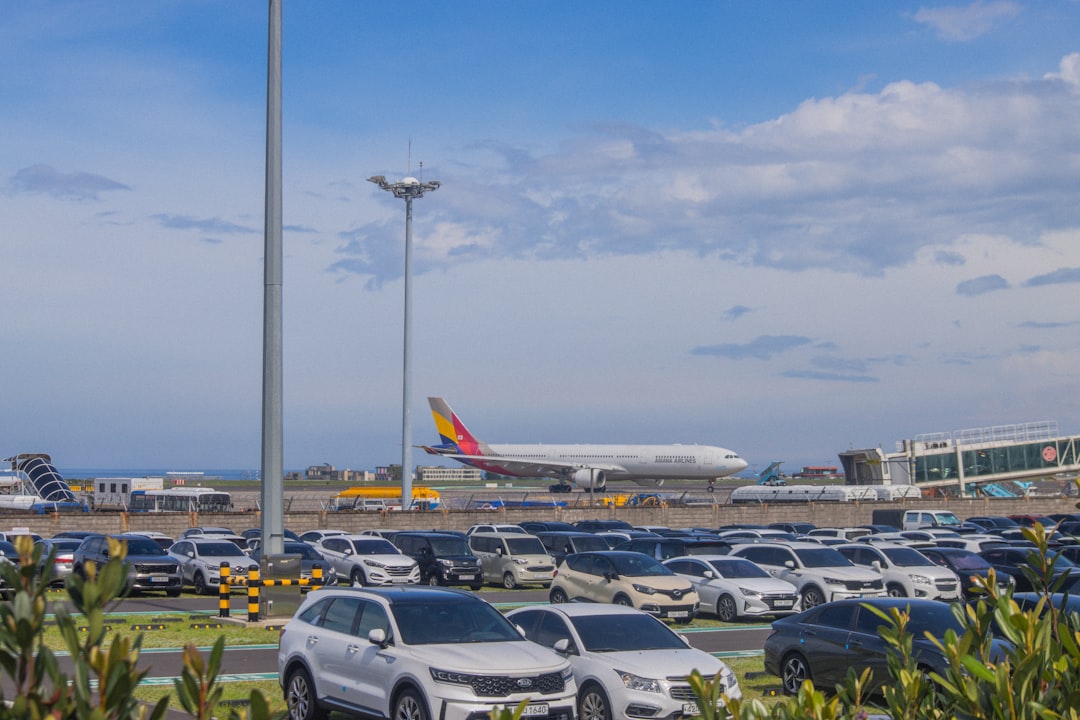 Airplane taxiing on runway with cars in foreground.