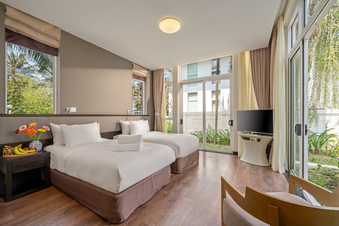 Modern hotel room with two beds and large windows.