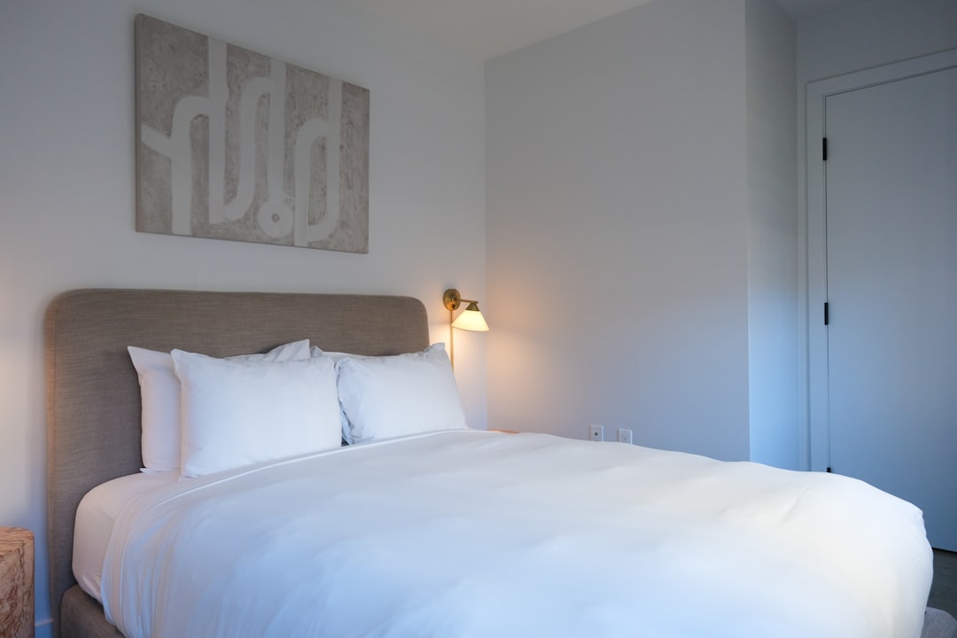 A neatly made bed with white linens and pillows.